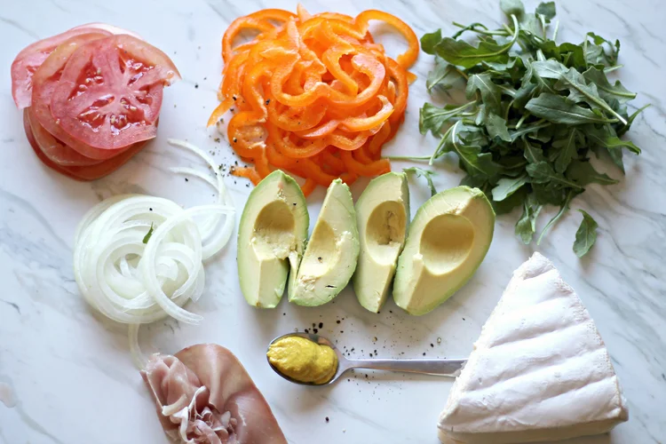 You will need: Thoroughly toasted Ezekiel Bread. I use the low sodium one that comes in an orange bag. 1/2 avocado thinly sliced bell pepper thinly sliced beef steak tomato thinly sliced onion, white or red arugula brie cheese mustard prosciutto 