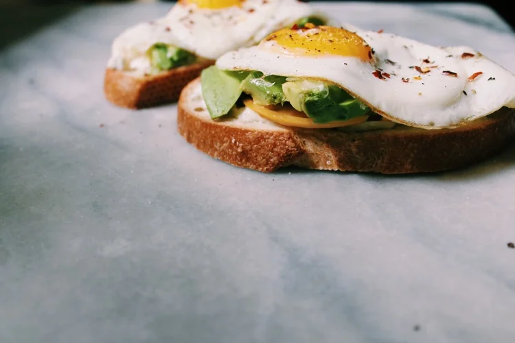 Aioli: 1/3 cup mayo 1/4 cup feta juice of 1 lemon 1 large garlic clove scant 1/4 tsp of basil Throw all ingredients into food processor, mix until smooth. For Toast: 2 pieces of sourdough bread toasted 1 heirloom tomato 1 avocado 2 eggs pinch of salt fresh ground pepper pinch of crushed red pepper Toast the bread and fry both eggs. Assemble like the following photos. 
