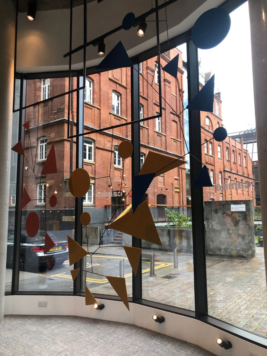 metal sculptures hung by a window shop front