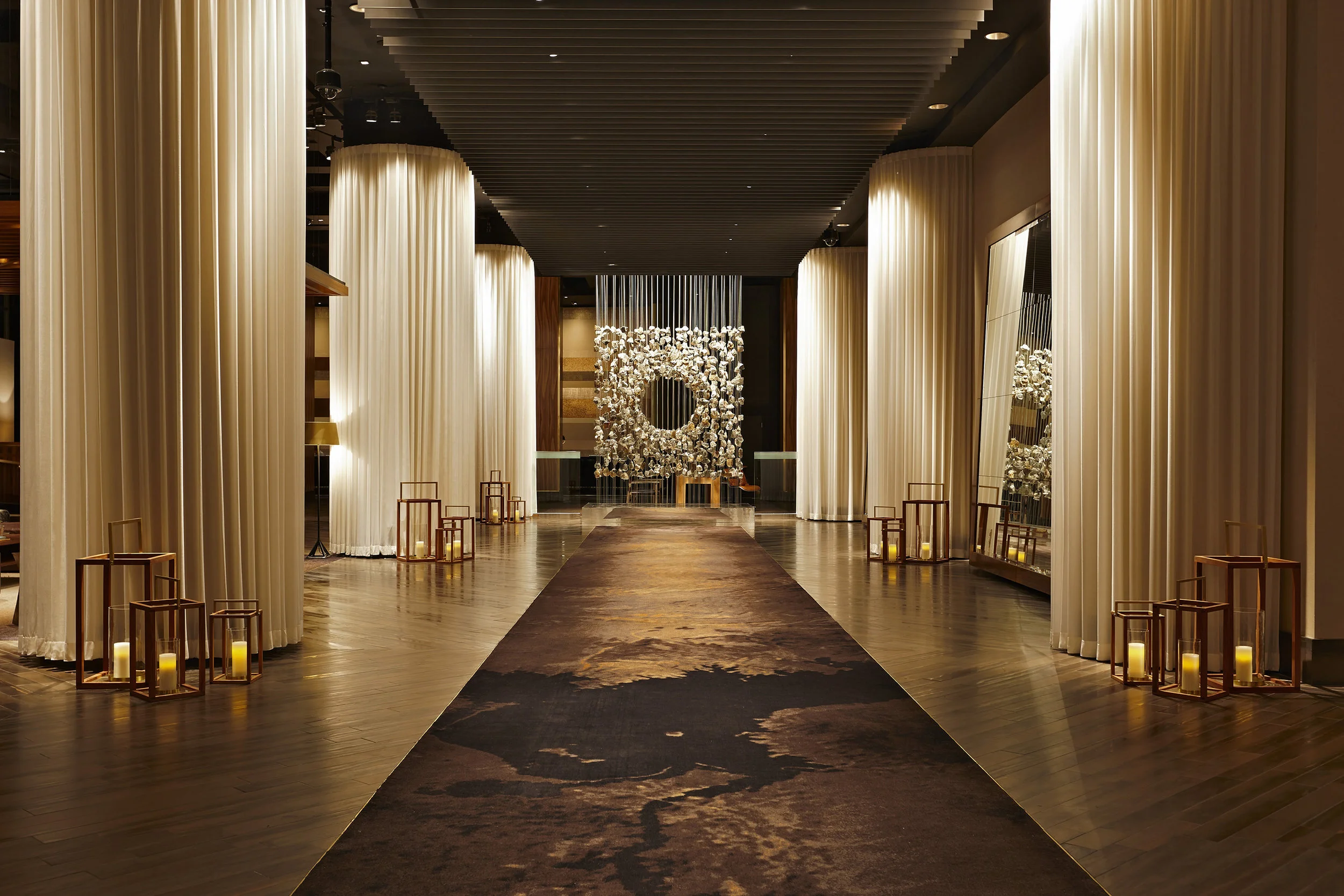 The lobby is lined with structural columns that are hidden behind sheer drapery, making this space feel warm and cozy. These sheer drapes also give the space that little touch of sexiness, reminding you of bed sheets. 
