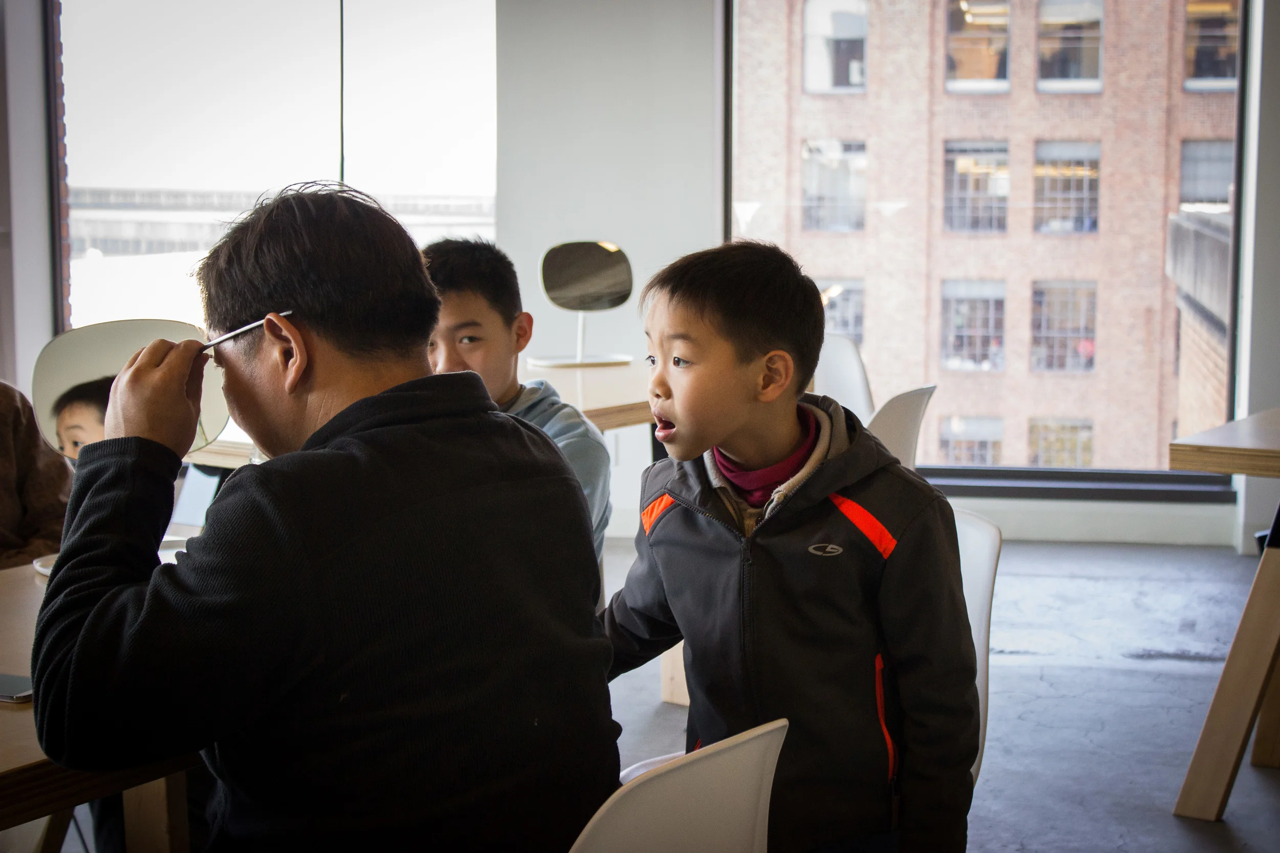As an Explorer tries on Glass for the first time, his sons look on.