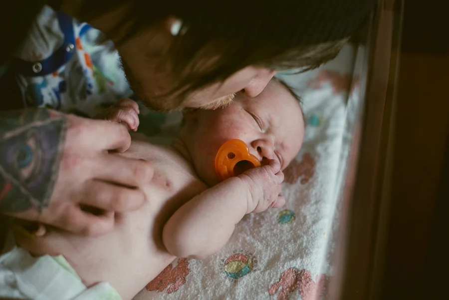 father kissing newborn