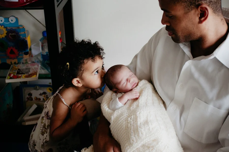 toddler kissing newborns head