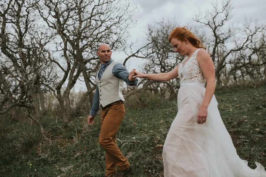 groom leading bride through woods