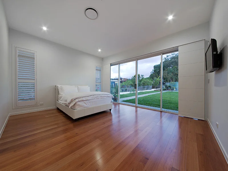 Huge master bedroom, polished timber flooring & large stacker doors. House design by Empire Design & Drafting