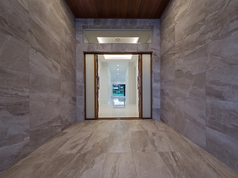 Tiled entry with feature timber doors. House design by Empire Design & Drafting