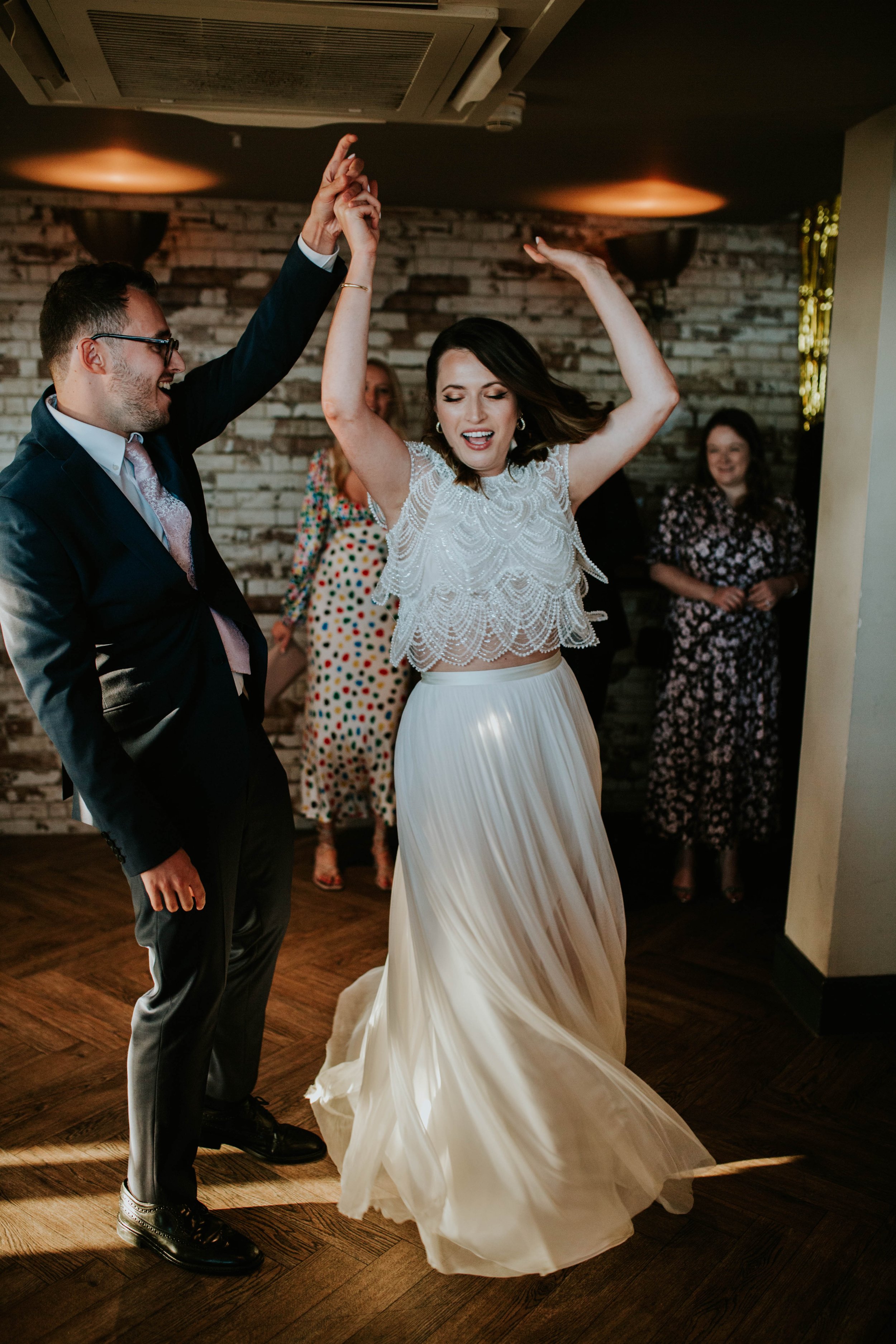  A bride and groom dance together, the bride is mid twirl and has a big smile on her face.  