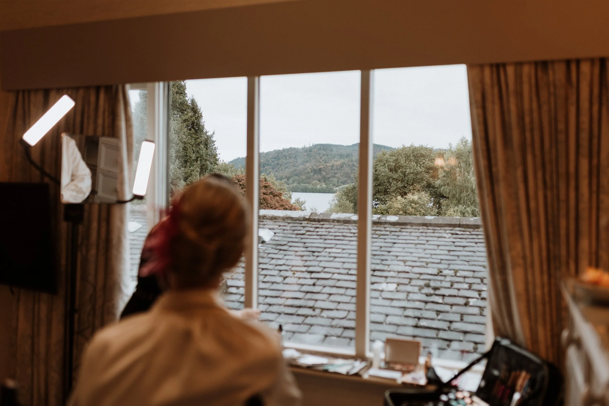  The mother of the bride looks out the window on her daughters wedding morning, the view from the window is of Lake Windermere.  