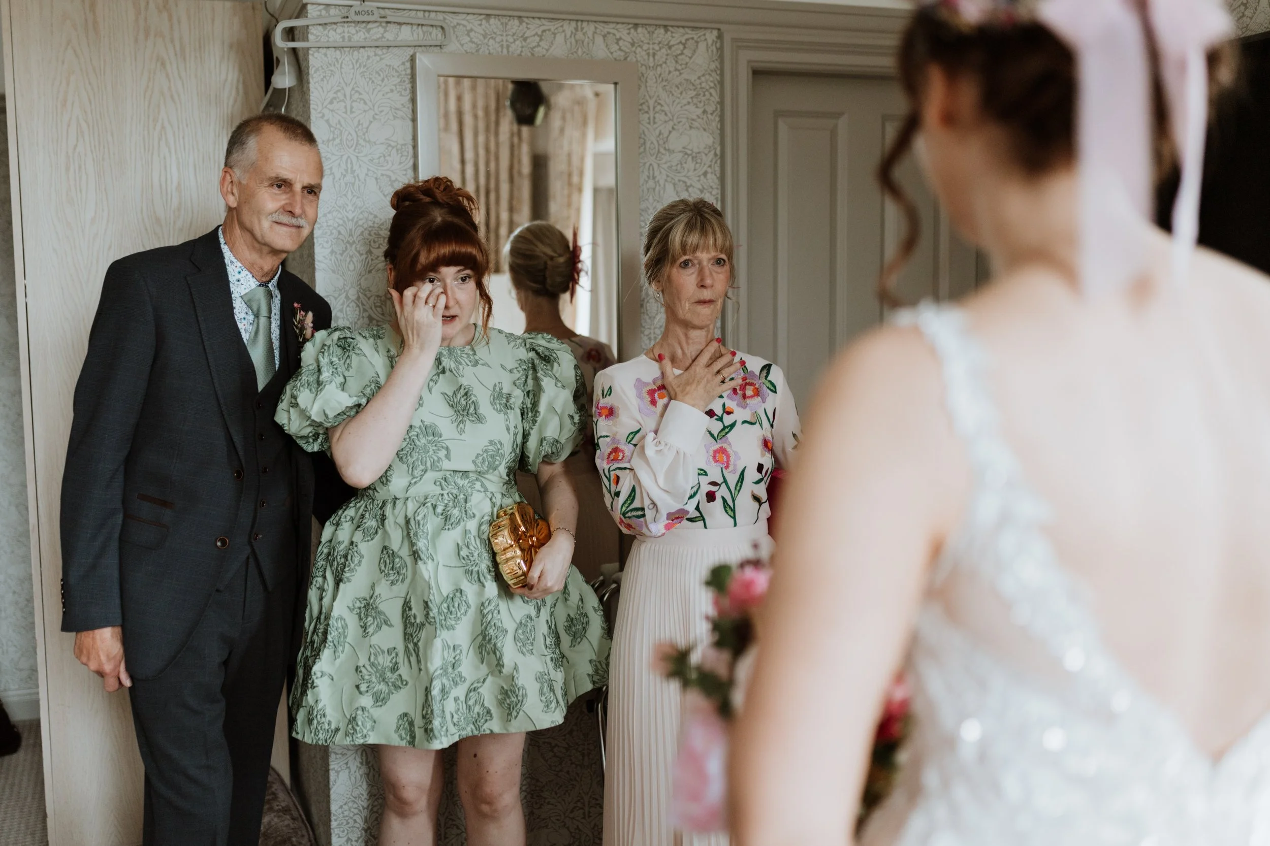  Family members wipe their tears as they see the bride in her dress for the first time. 