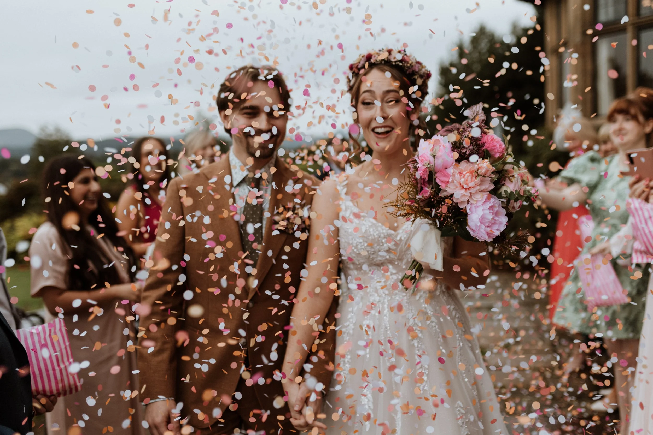  A bride and groom laugh as they walk through their confetti tunnel in the Lake District.  