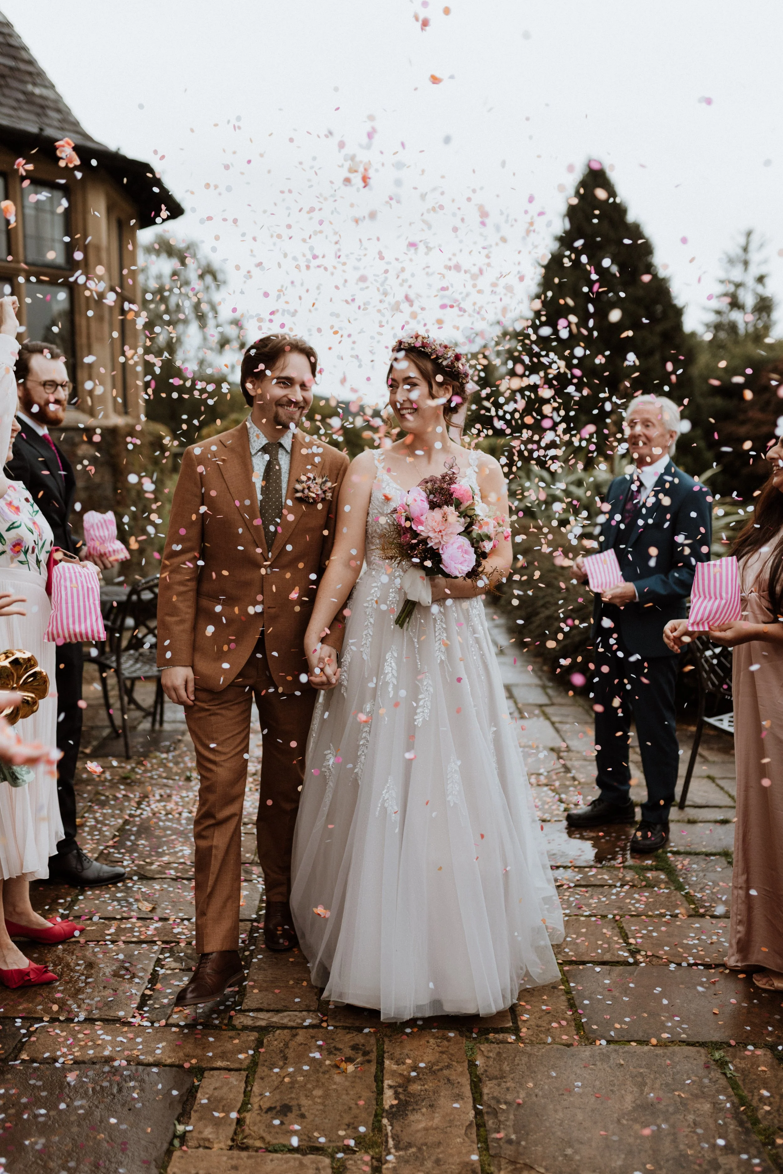  A bride and groom walk through their confetti tunnel on a rainy day in the Lake District.  