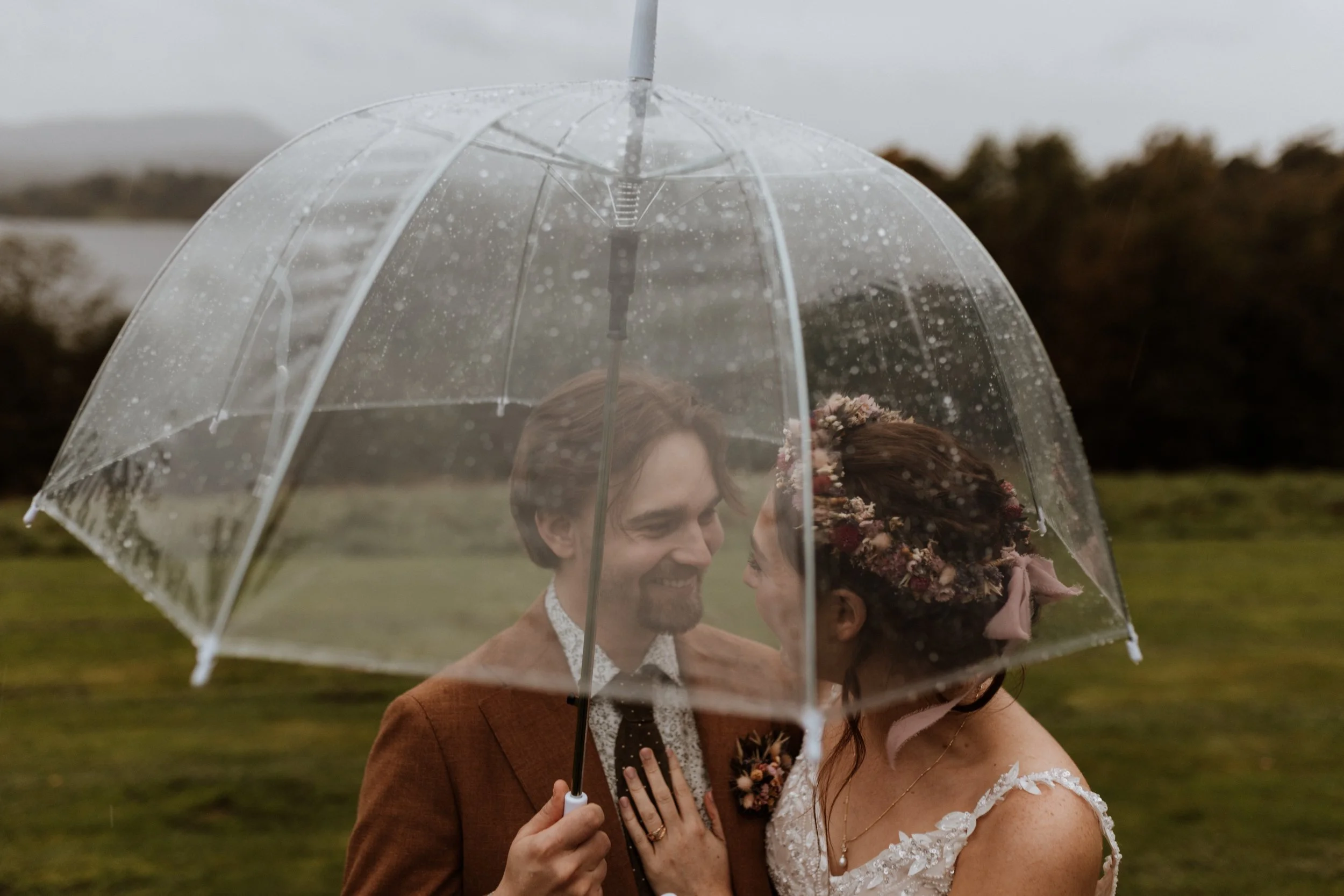  Bride and groom under an umbrella during a rainy Lake District wedding at Cragwood Hotel. 