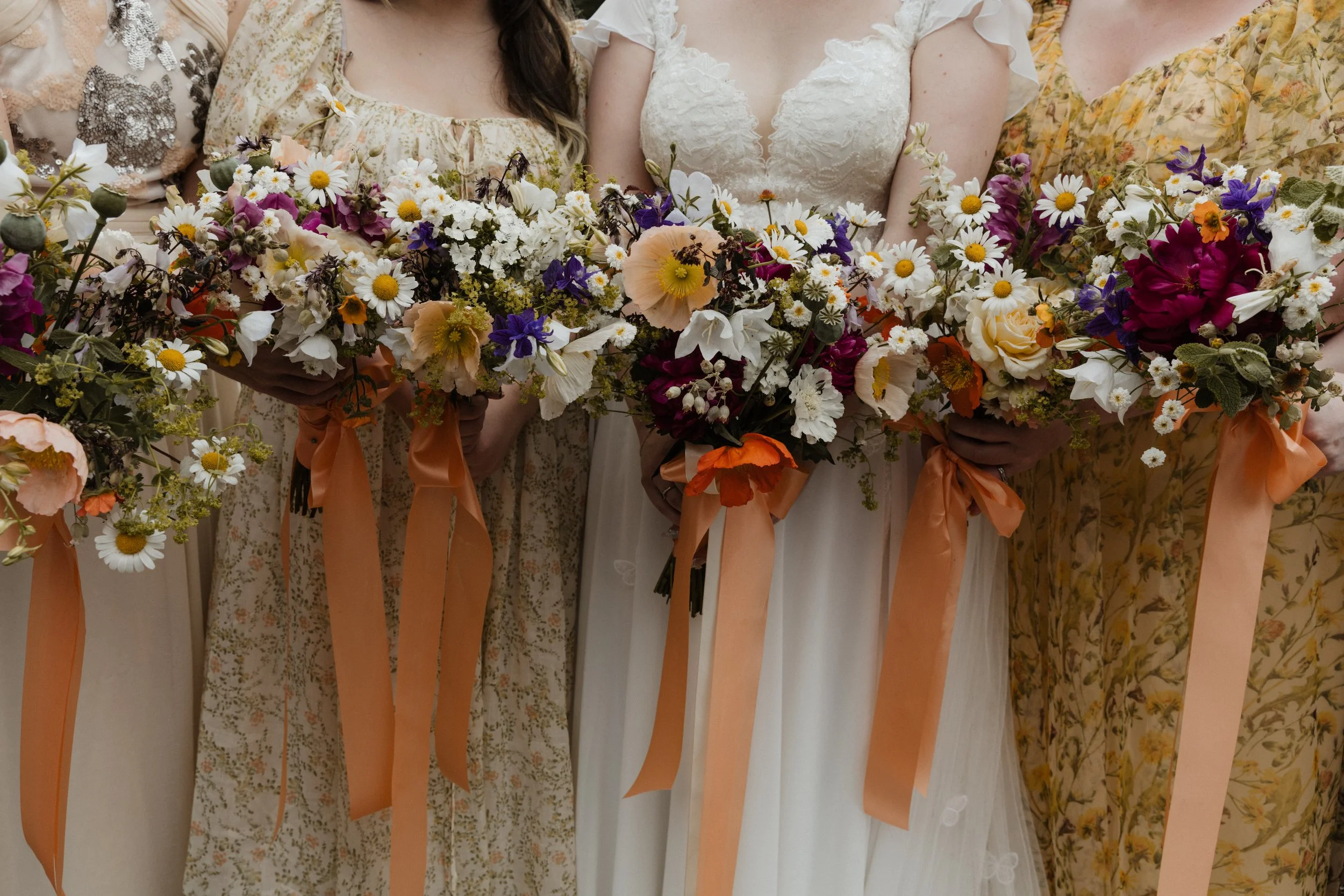 A bride and her bridesmaids hold their bouquets together.