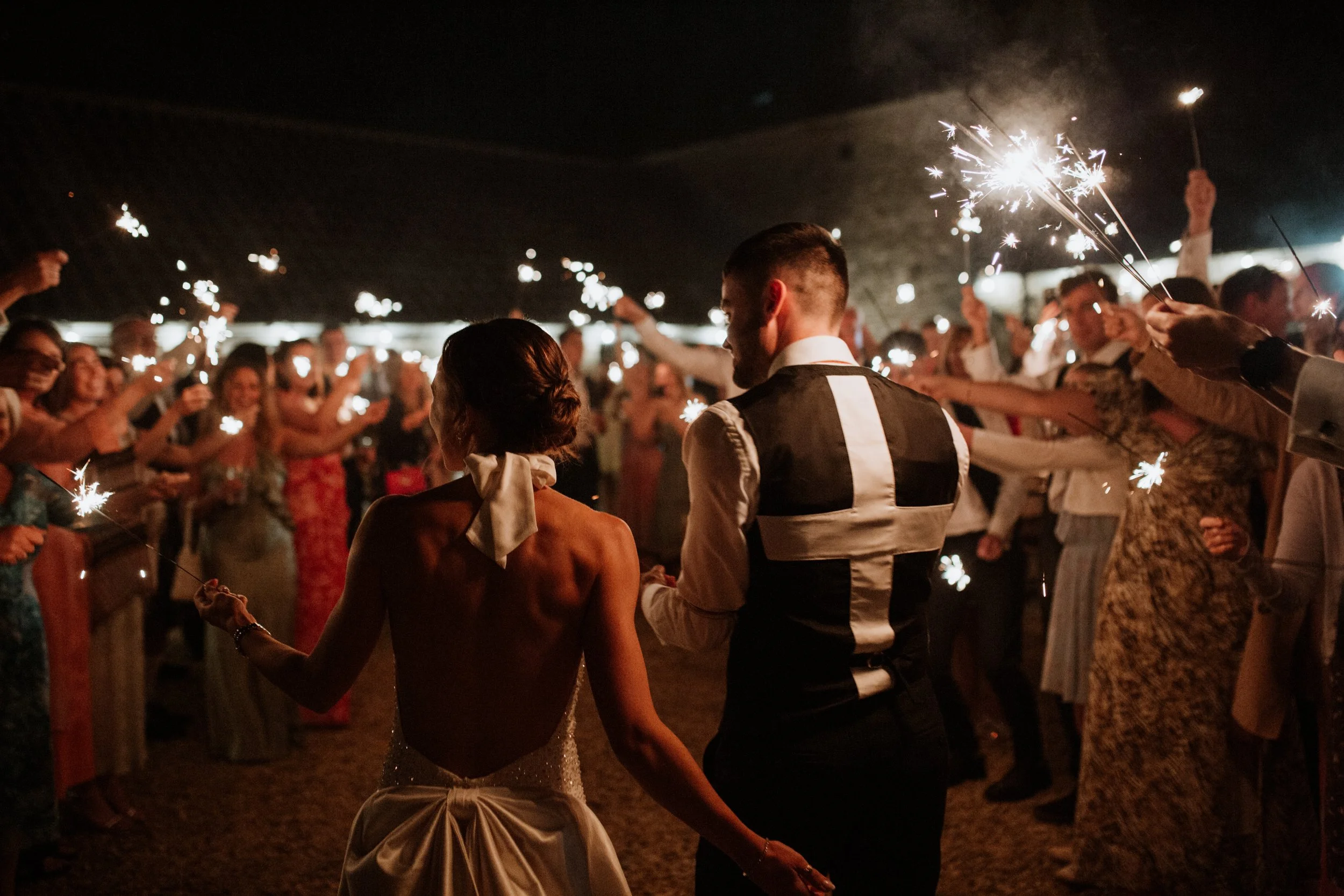 A bride and groom, look out at their guests during their sparkler exit.