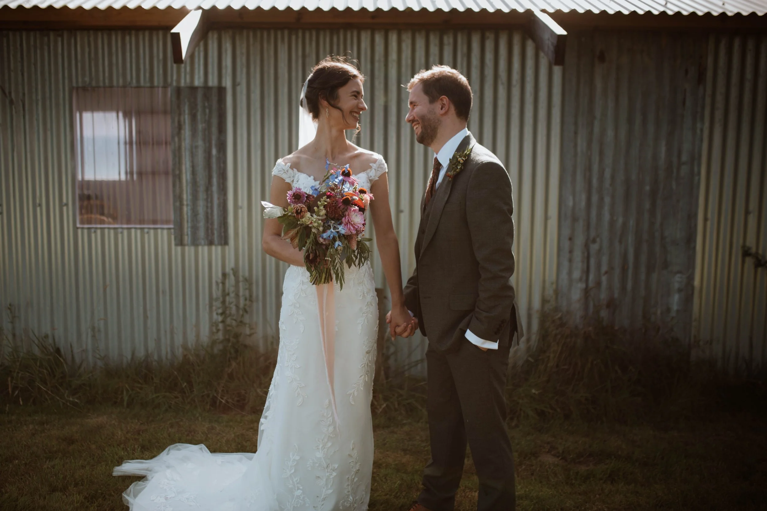 A bride and groom hold hands and laugh on their wedding day at Hawthush Farm.