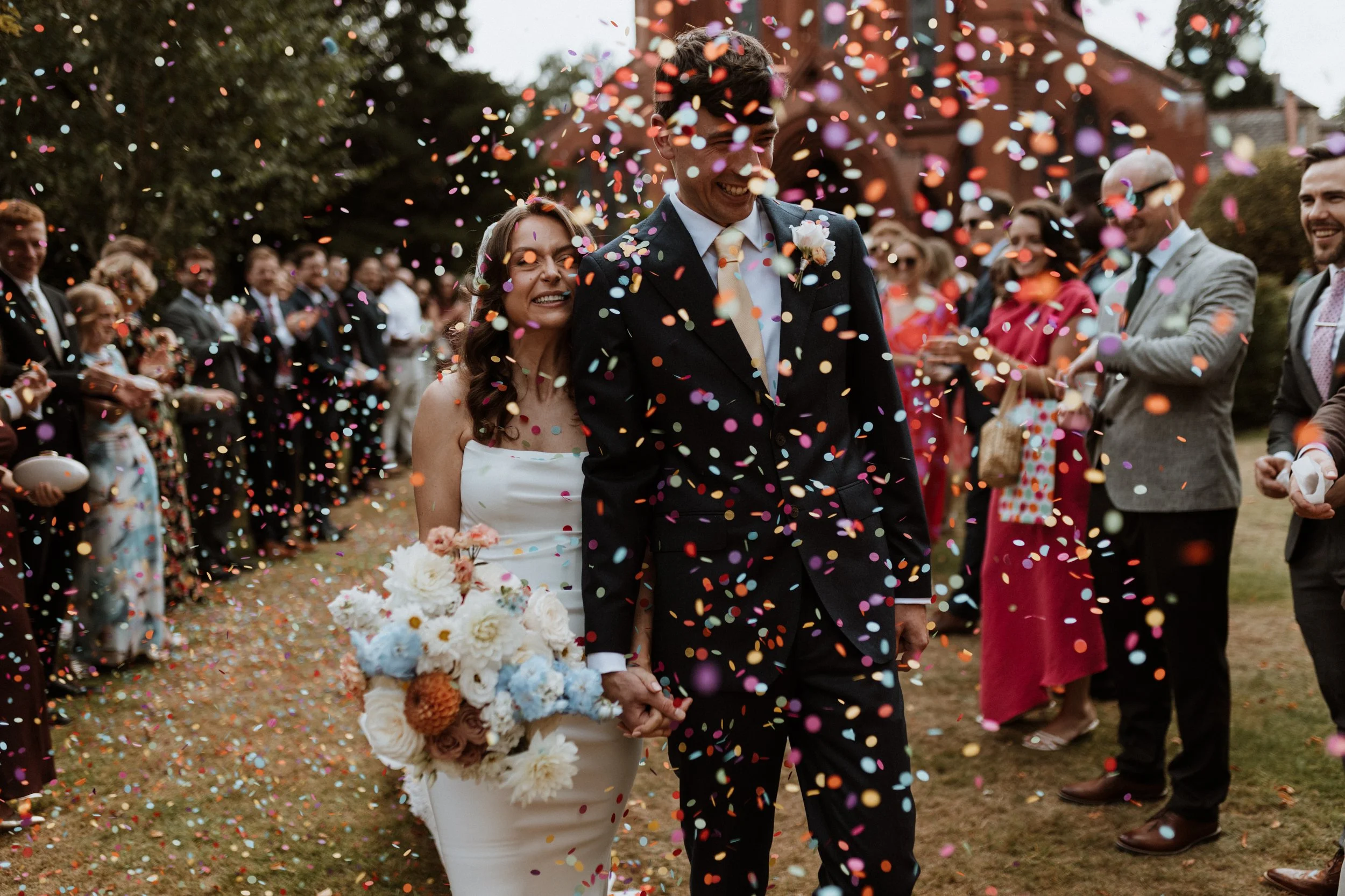 A bride and groom walk through a shower of confetti in Manchester