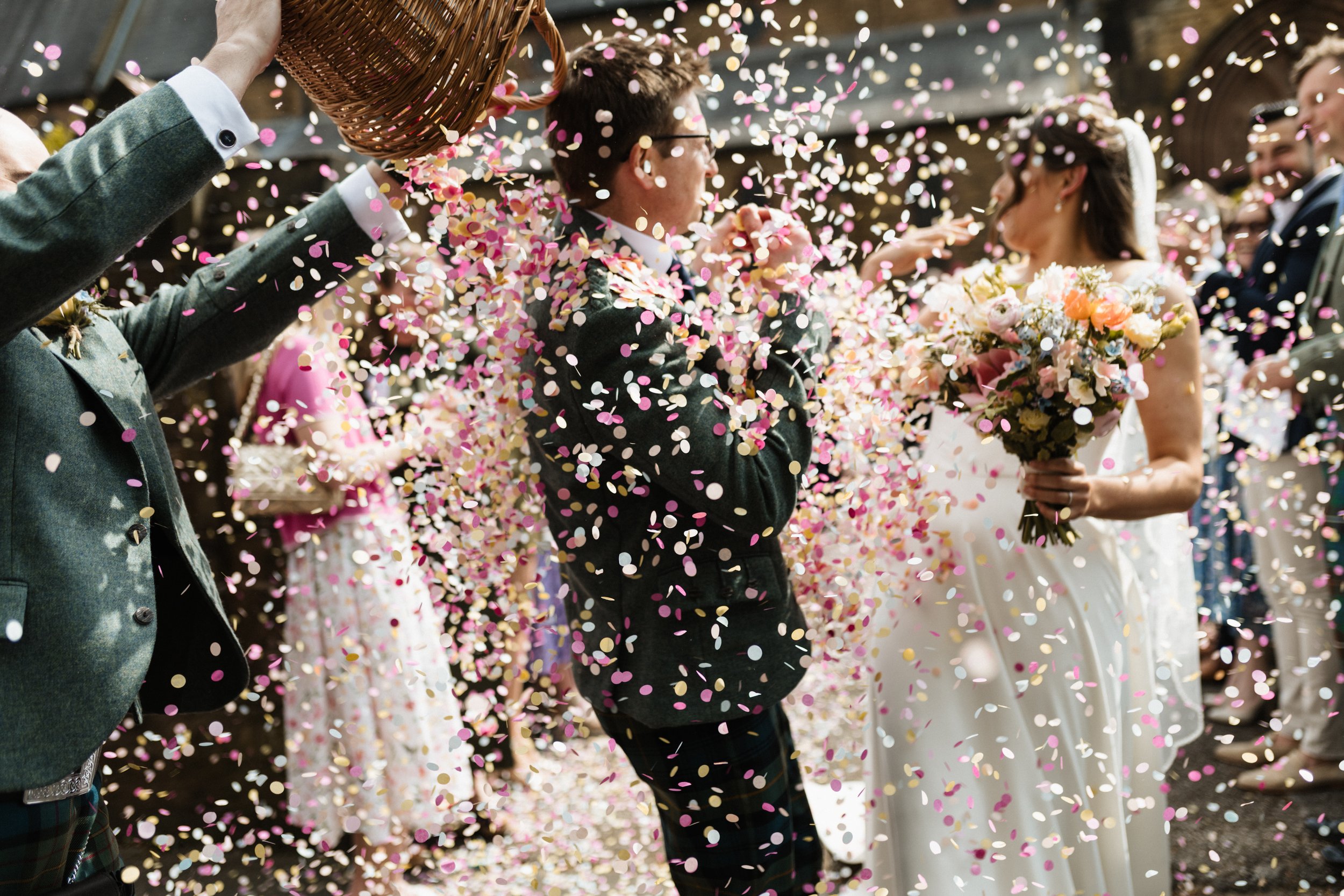 A bride and groom get showered in confetti on their wedding day.