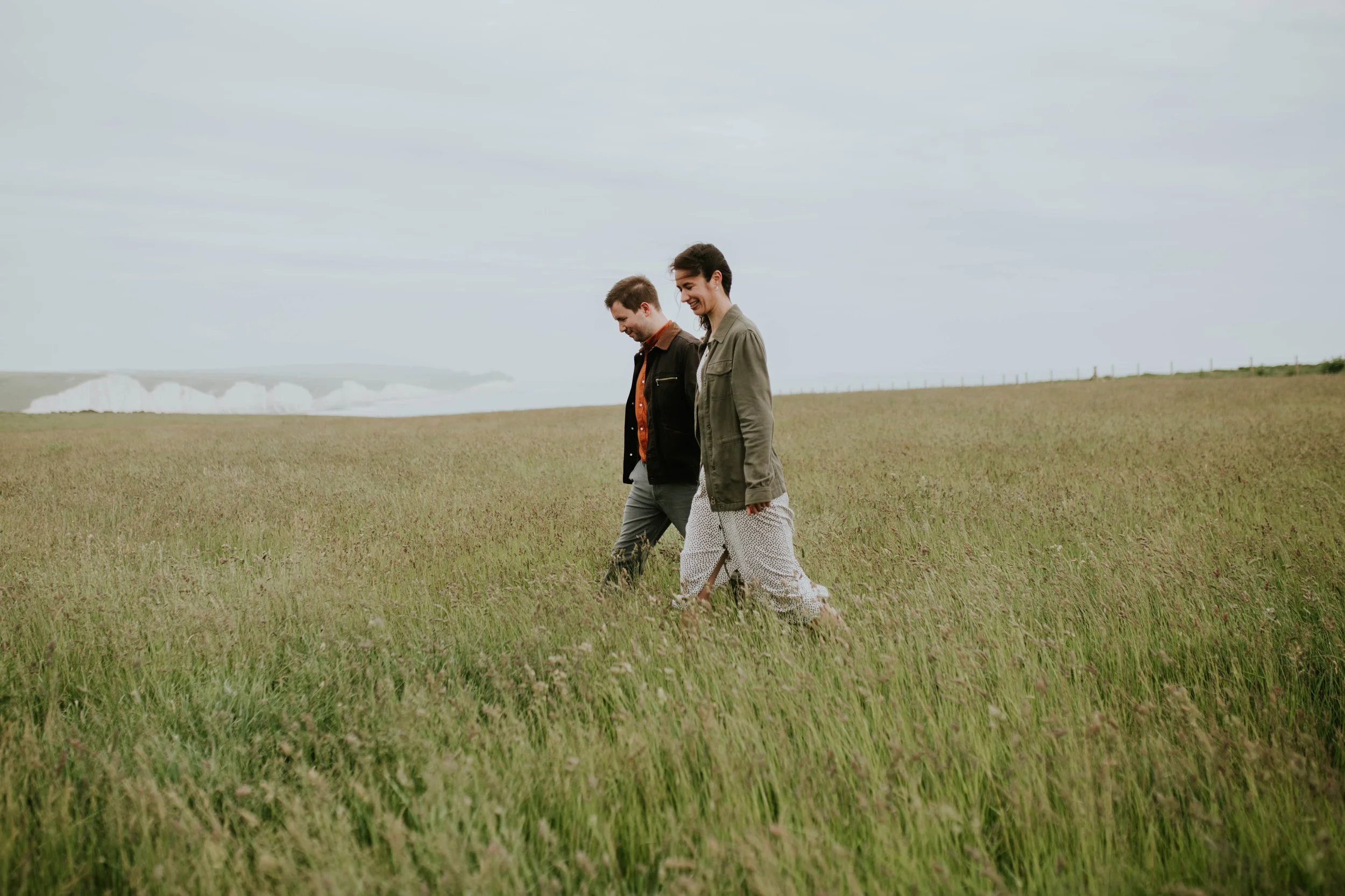 Newly engaged couple hold hands and walk together.