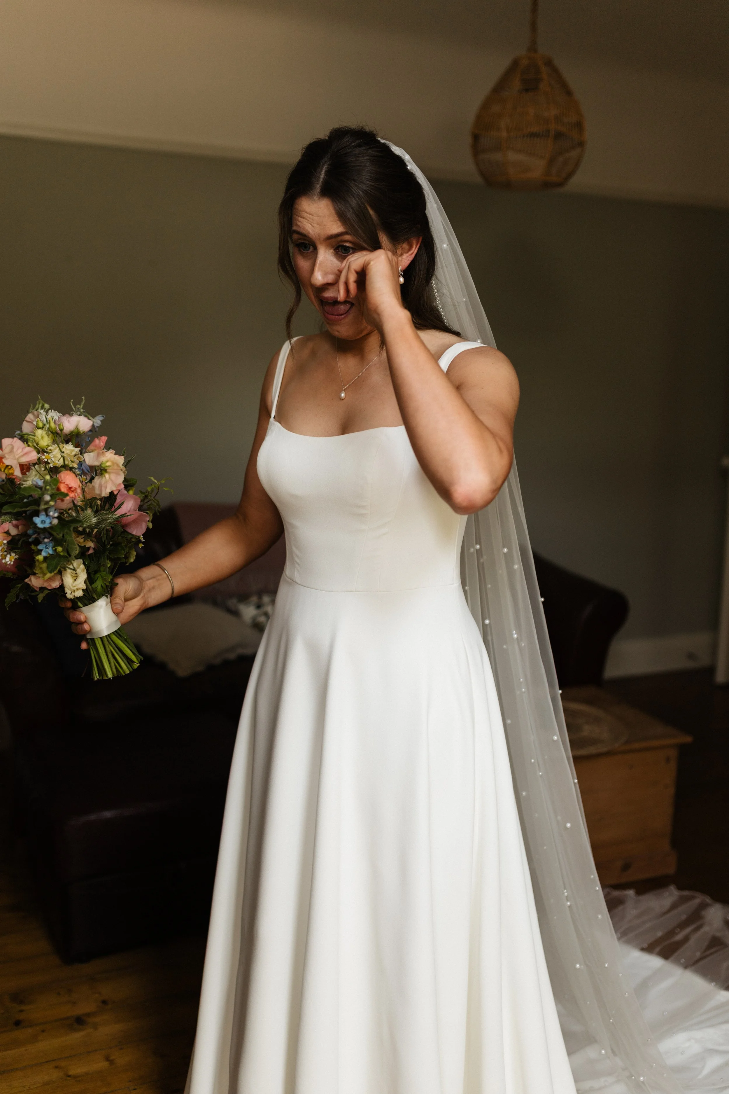 A bride wipes a tear from her face on her wedding day.