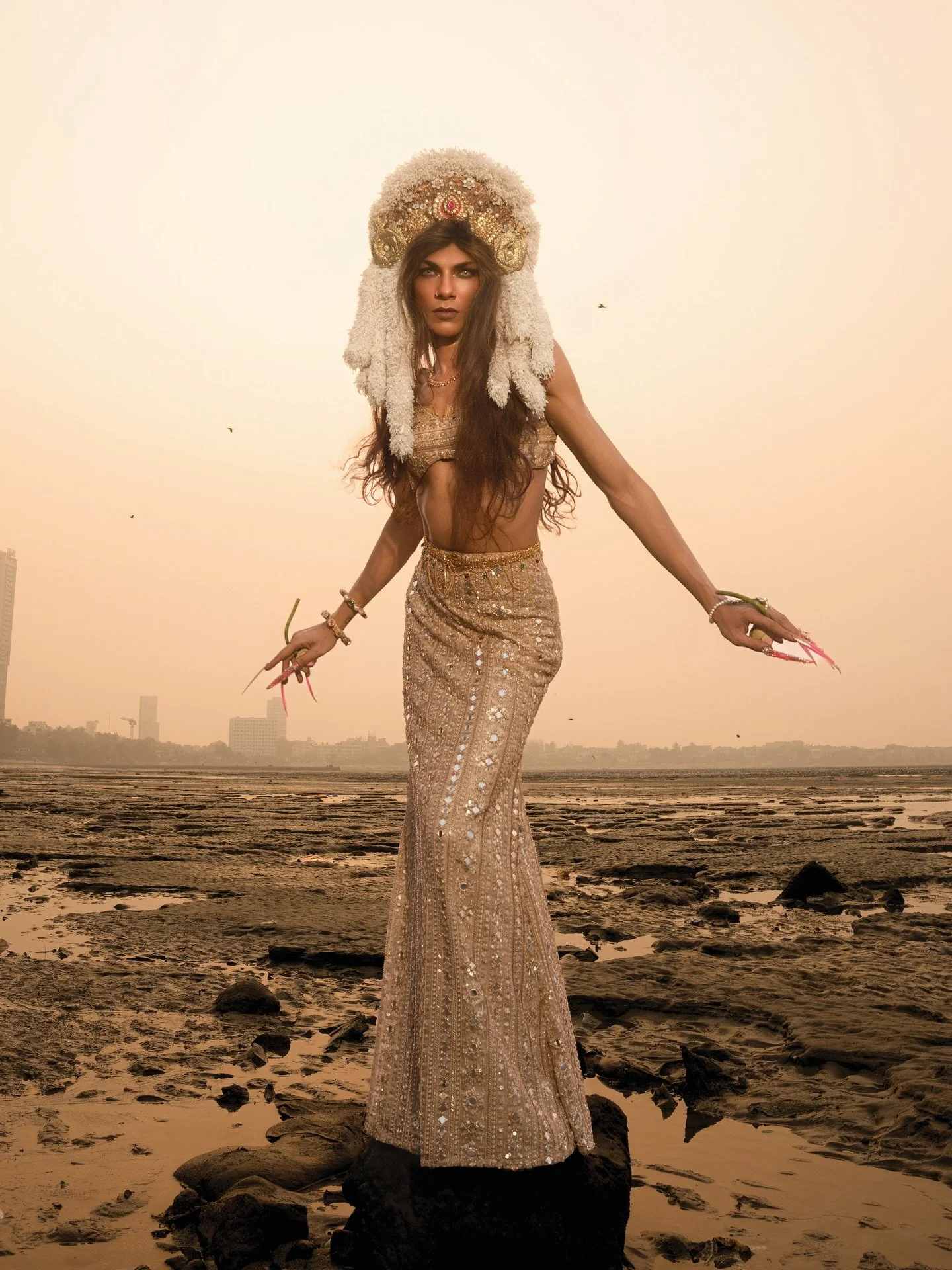 She rises where the ocean meets the sky,
draped in gold, holding a lotus like a quiet spell.
Part universe, part desire, part divine light.
This Pride weekend, we honor the beauty of being seen &mdash;
radiant, sensual, and unapologetically whole. 🌊