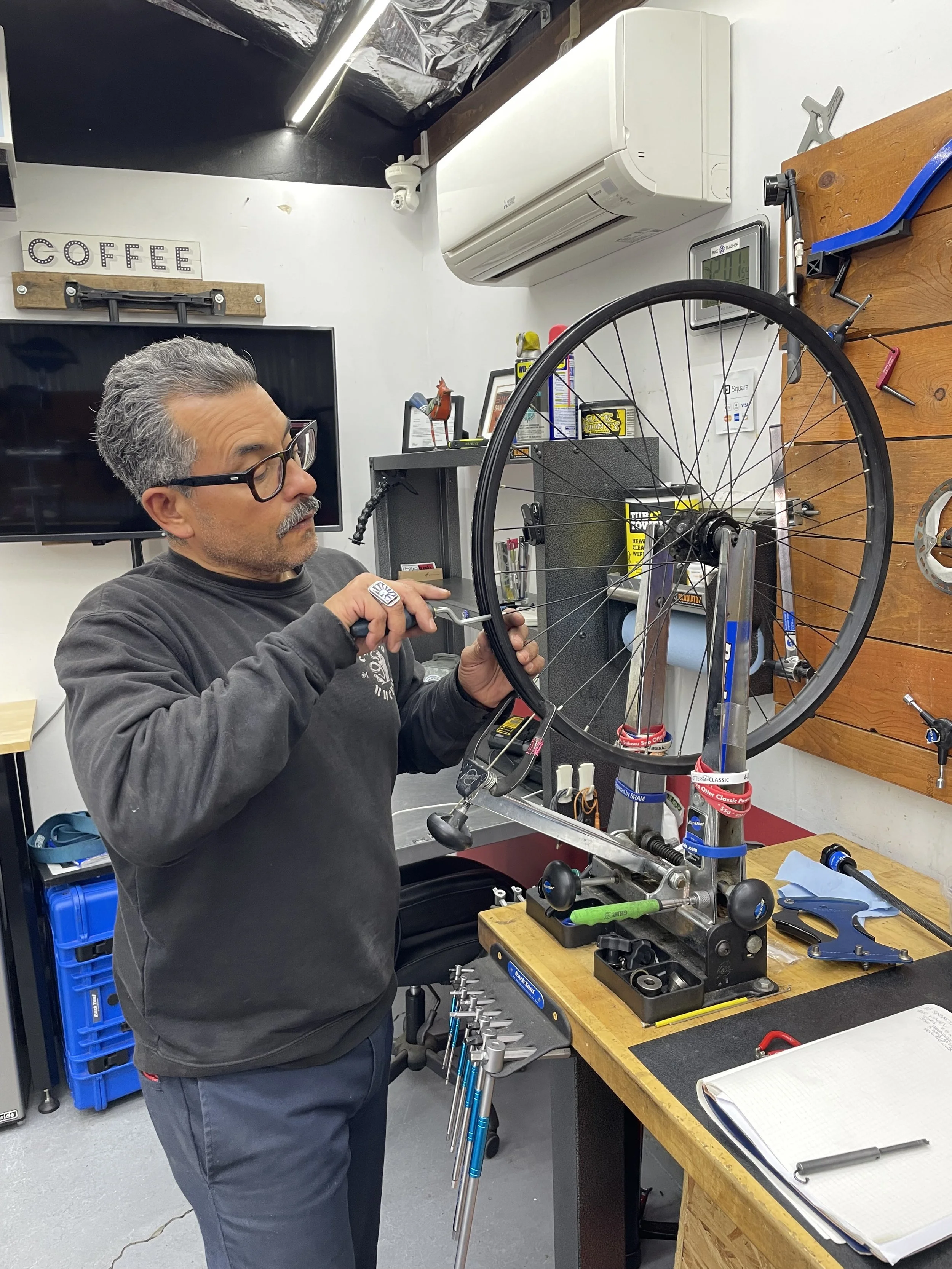 40-hour Bike Teacher student working on bicycle wheel adjustments during hands-on mechanic training in San Jose, California