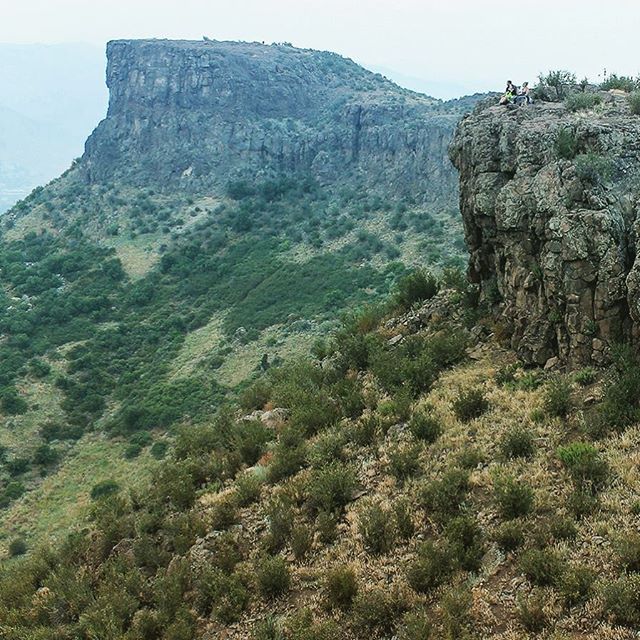 View of Castle Rock (left, in distance) on South Table Mountain (August 22, 2015). Two prominent basalt flows (62-64 Ma) are exposed at the crest of the &quot;table&quot;. Note people for scale (on precipice, right foreground). || #basalt #geology #g