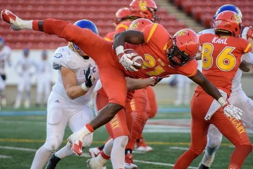 Calgary Dinos running back Jeshrun Antwi goes airborne during a 4th quarter carry in the Hardy Cup. The Dinos downed the Thunderbirds 46-43 at McMahon Stadium in Calgary on Saturday November 12, 2016.- Maxwell Mawji, Capture Candy.