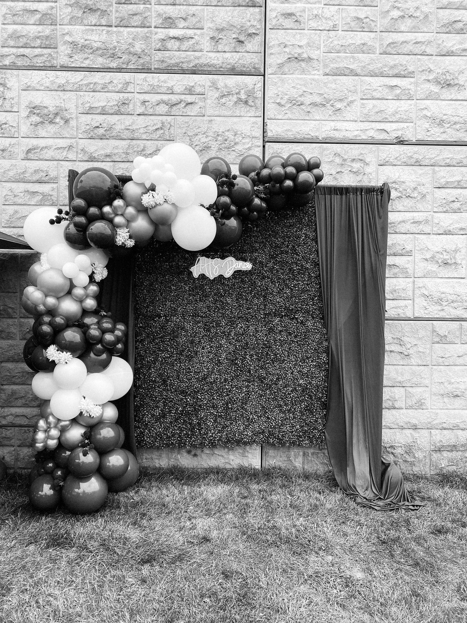  A balloon arch frames a greenery backdrop for unique photobooth decor at a wedding 