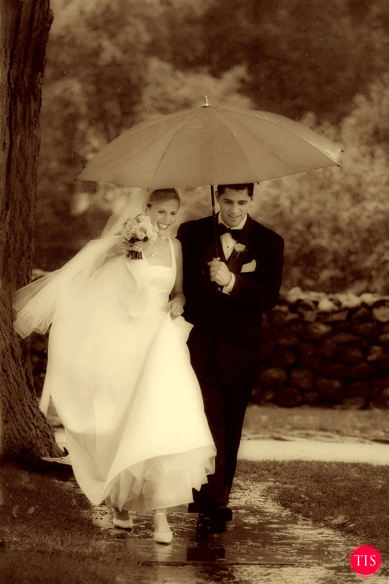 A bride and groom walk in the rain headed towards their tented reception at a private wedding venue in Connecticut. Moment captured by Maring Visuals
