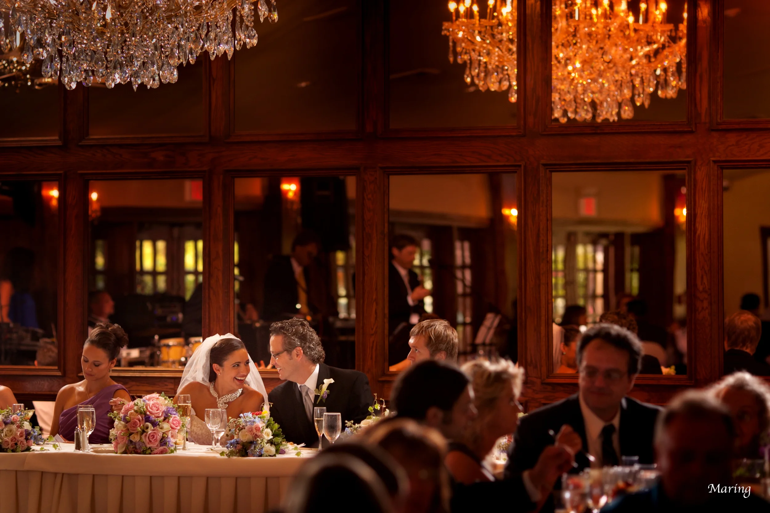 A bride and groom dine together at their head table making sure to eat before greeting tables.