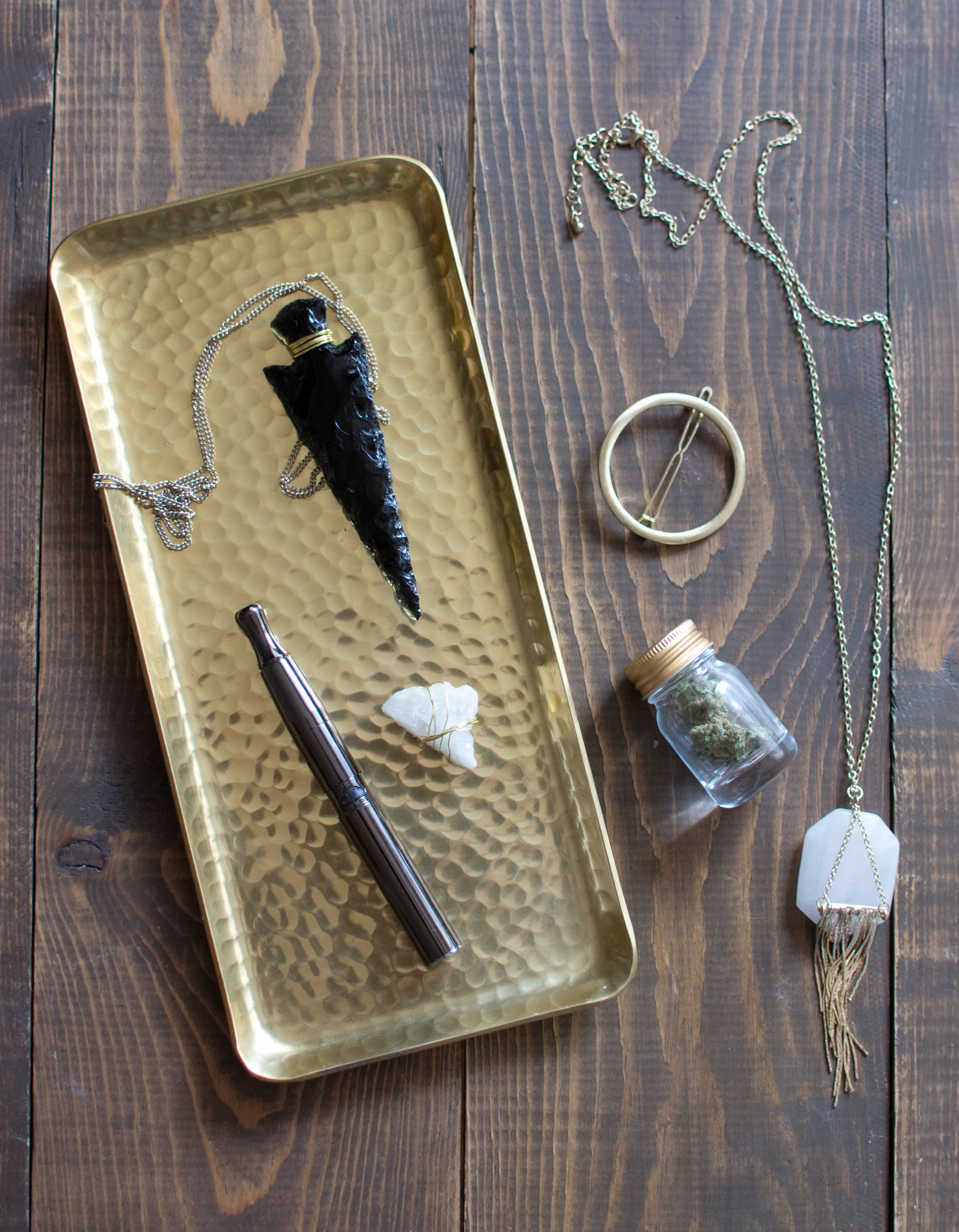 Gold tray from Hobby Lobby / Puffco reloadable concentrate vape pen / Obsidian arrow head from crystal shop in Sedona / Quartz crystal from Earthbound / Gold circle hair clip from Francescas / Quartz + Gold crystal necklace from Francescas / Miniature gold-lidded jar from Michael's / Durban Berry bud from The Farm Co. 