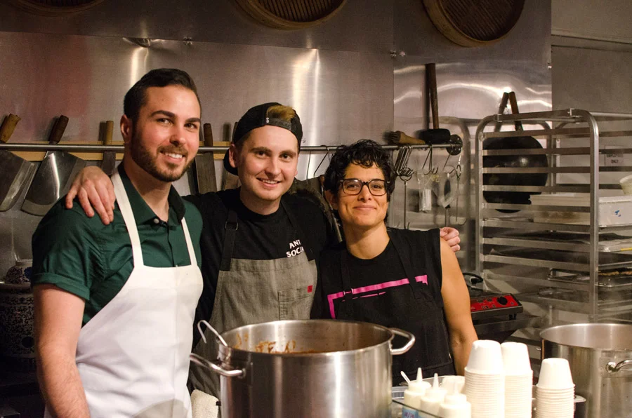 Liz Alpern (right) of Queer Soup Night, with soups (Julia’s Tortilla Soup with the Works and Nik’s Cocoa-Spiced Bean and Lentil Soup) prepared by Jesse Szewczyk (middle) and Kyle Bartone.