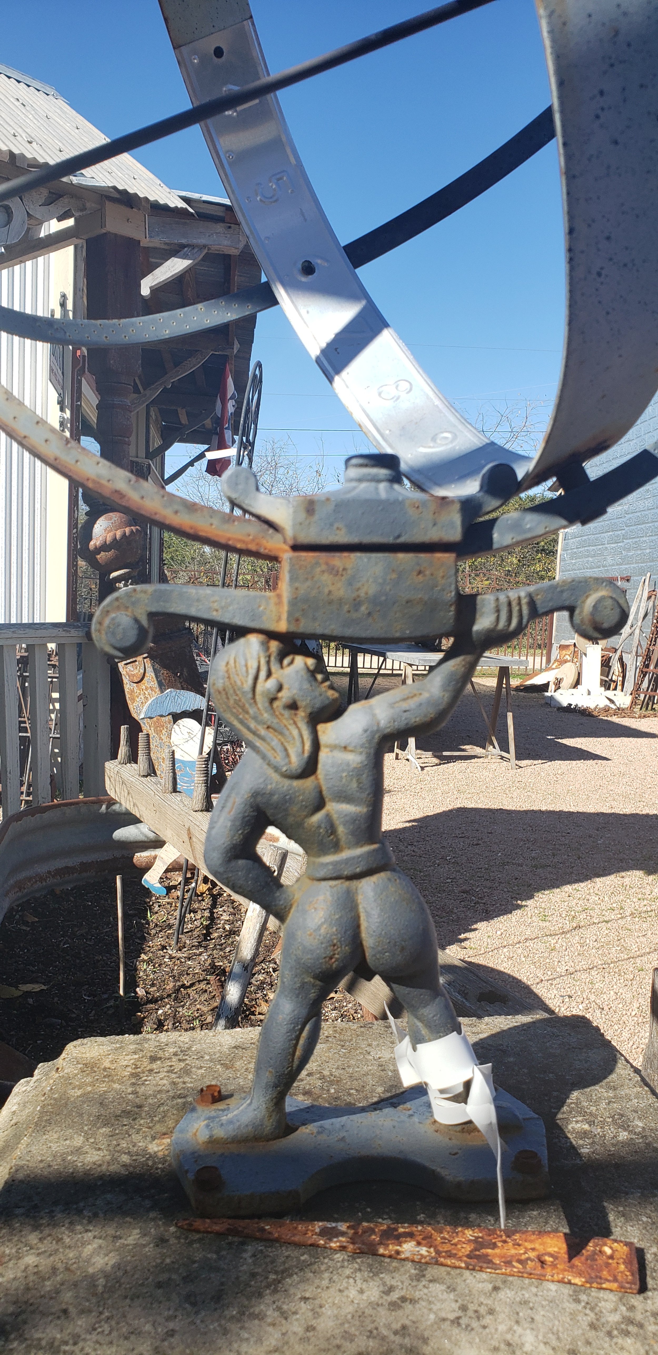 iron statue of man holding sundail