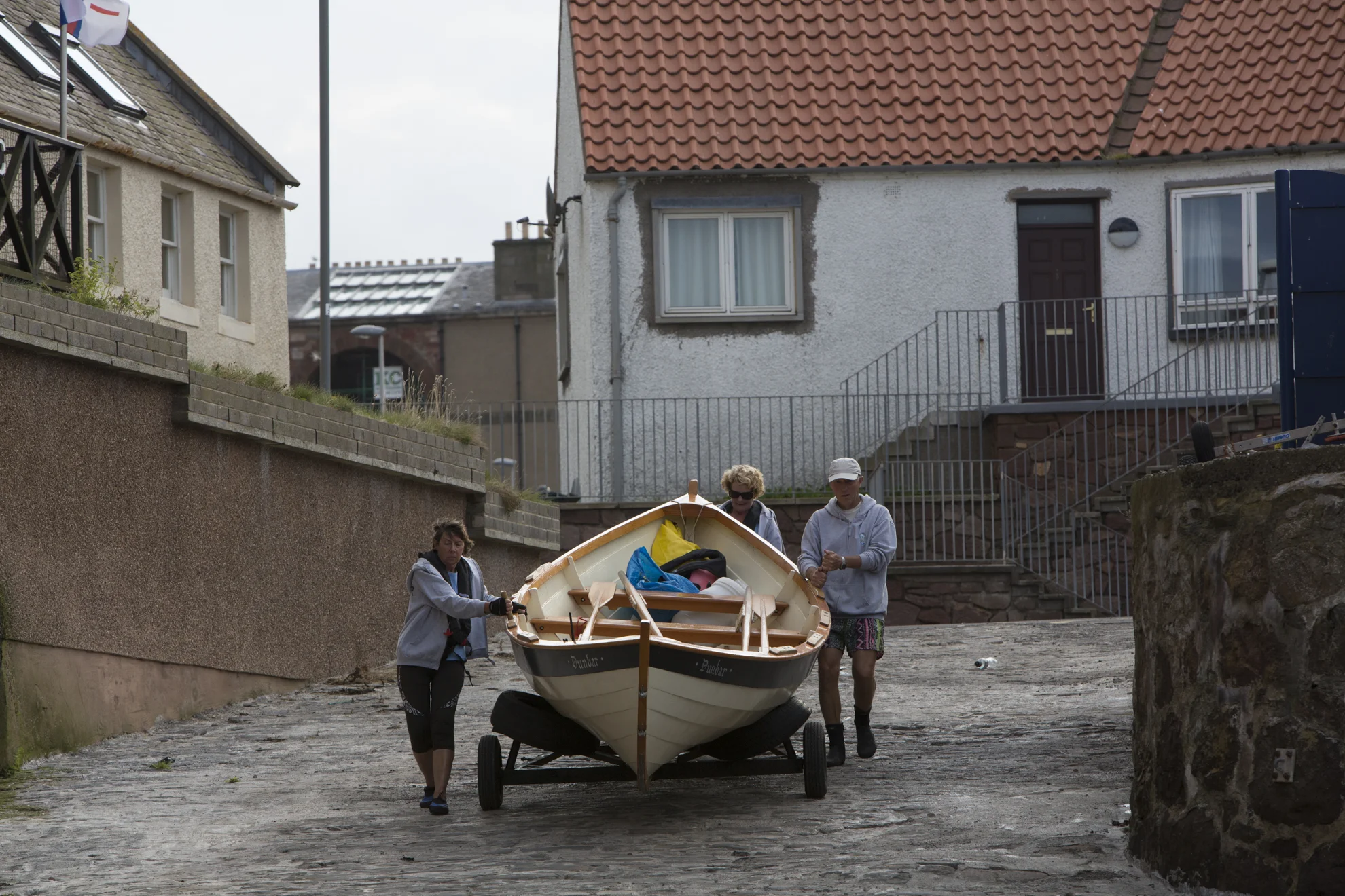 From left, Diana Mackie, Pamela Maule and Kenny Maule wheel the "Black Agnes" out to the water in Dunbar, Scotland.