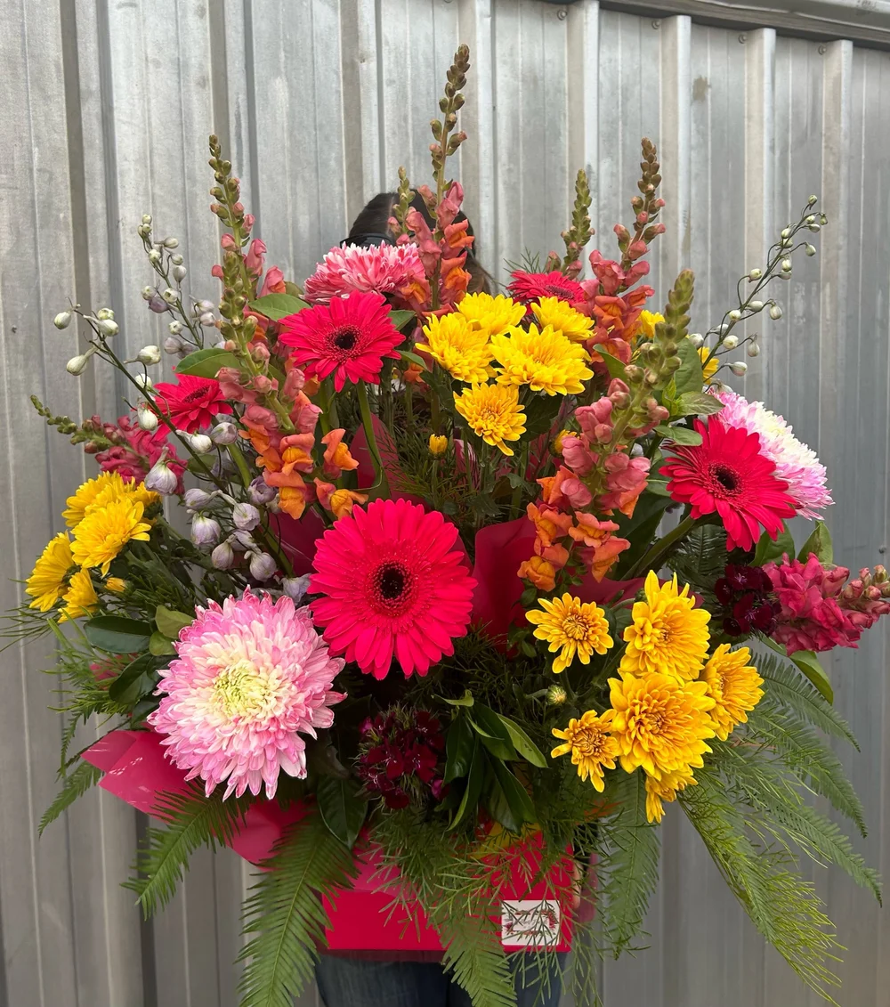 An arrangement made at Gatton Florist, photographed against the shop's iron wall
