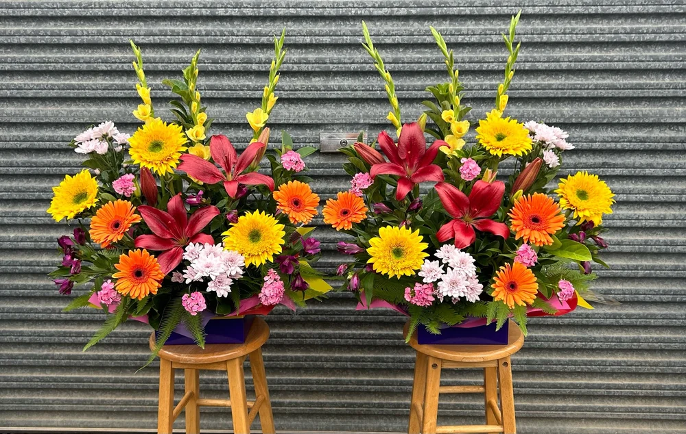 Two matching arrangements on stools against the shop's iron wall