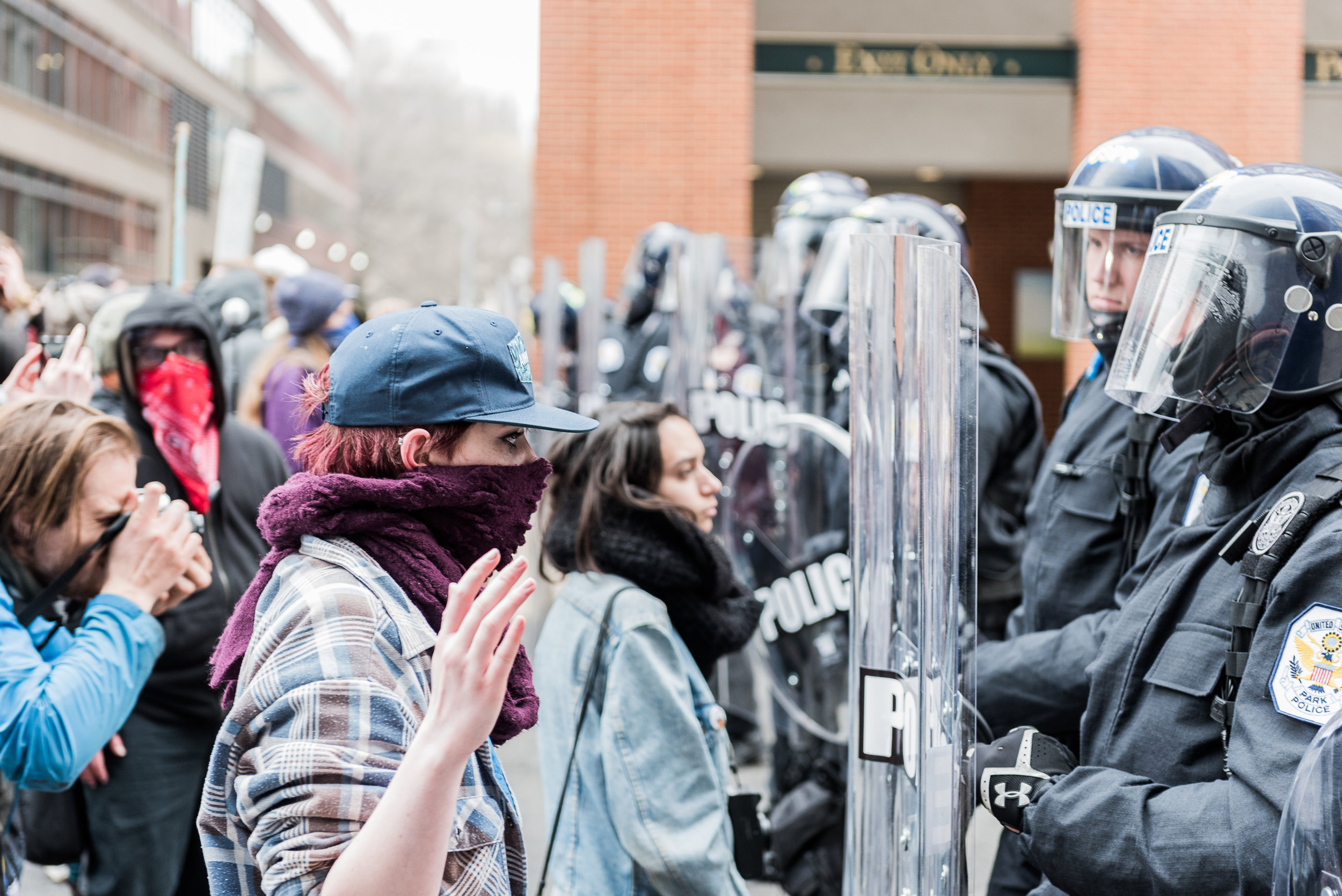 A protester stares down a police officer in riot gear on 12th Street, Friday, January 20, 2017.