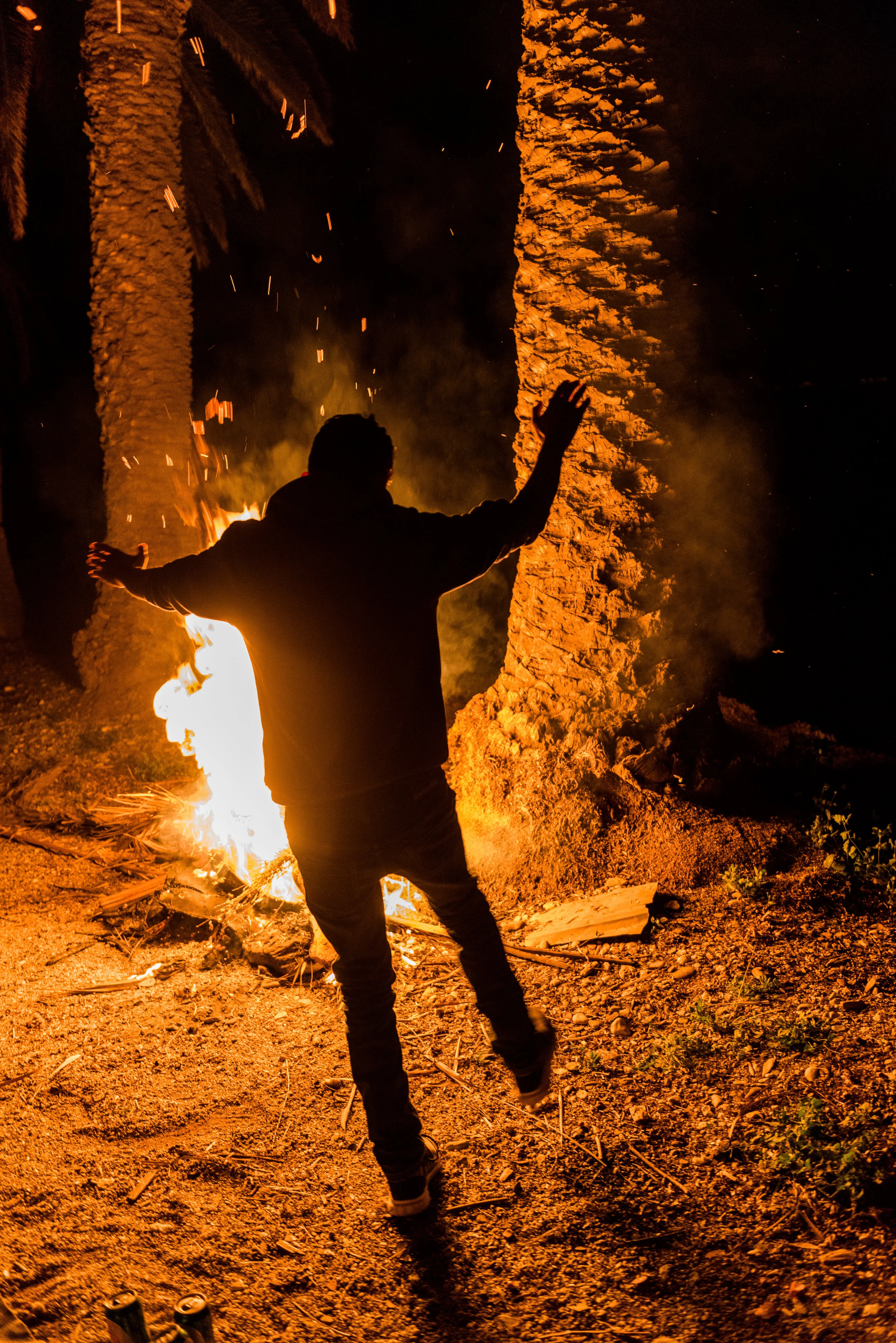 Aziz dances to the music in front of the roaring palm tree branch fire.