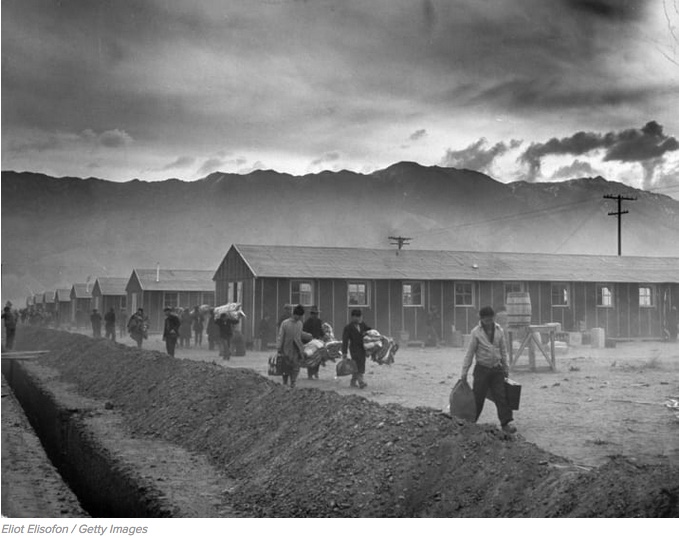 A group of Japanese-Americans arrive at the Manzanar incarceration camp carrying their belongings in 1942.