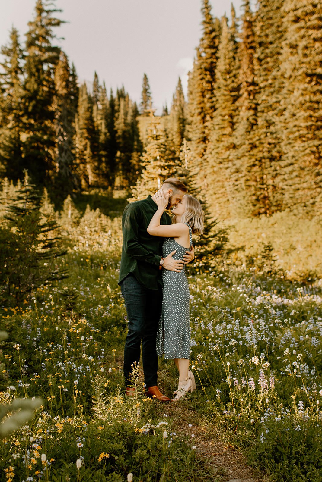 couple touching foreheads in a meadow in mt. rainier during their engagement photos