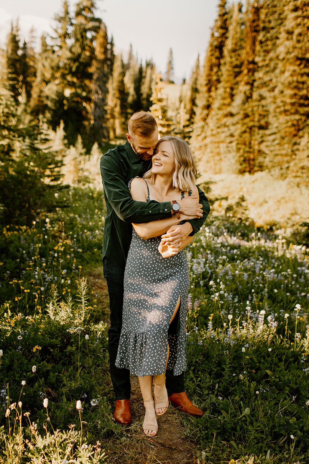 Fiance hugging his girl friend from behind in a meadow of wildflowers in mt. rainier national park