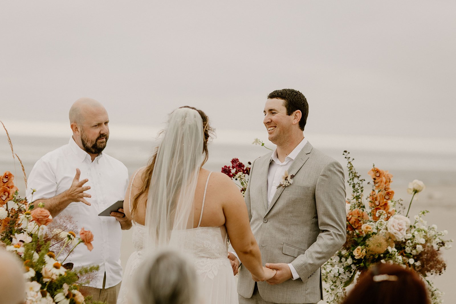 groom smiling at bride whole listening to the officiant