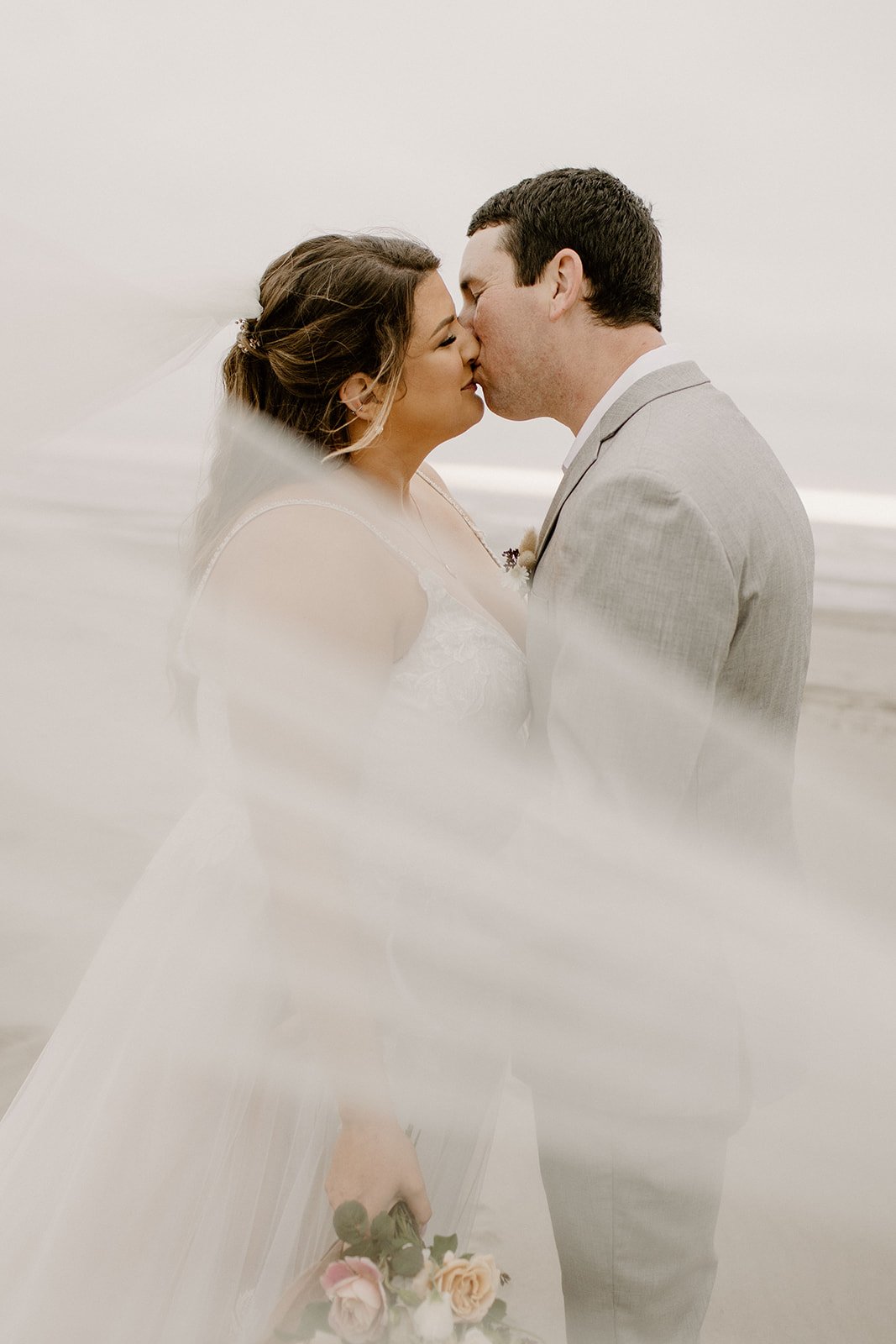 beautiful veil photo of bride and groom kissing
