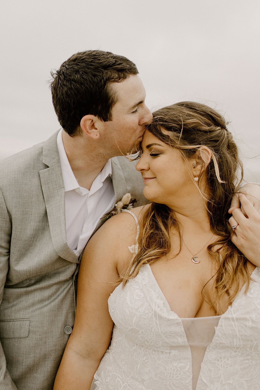 groom kissing bride on the forehead during beach wedding in coastal washington