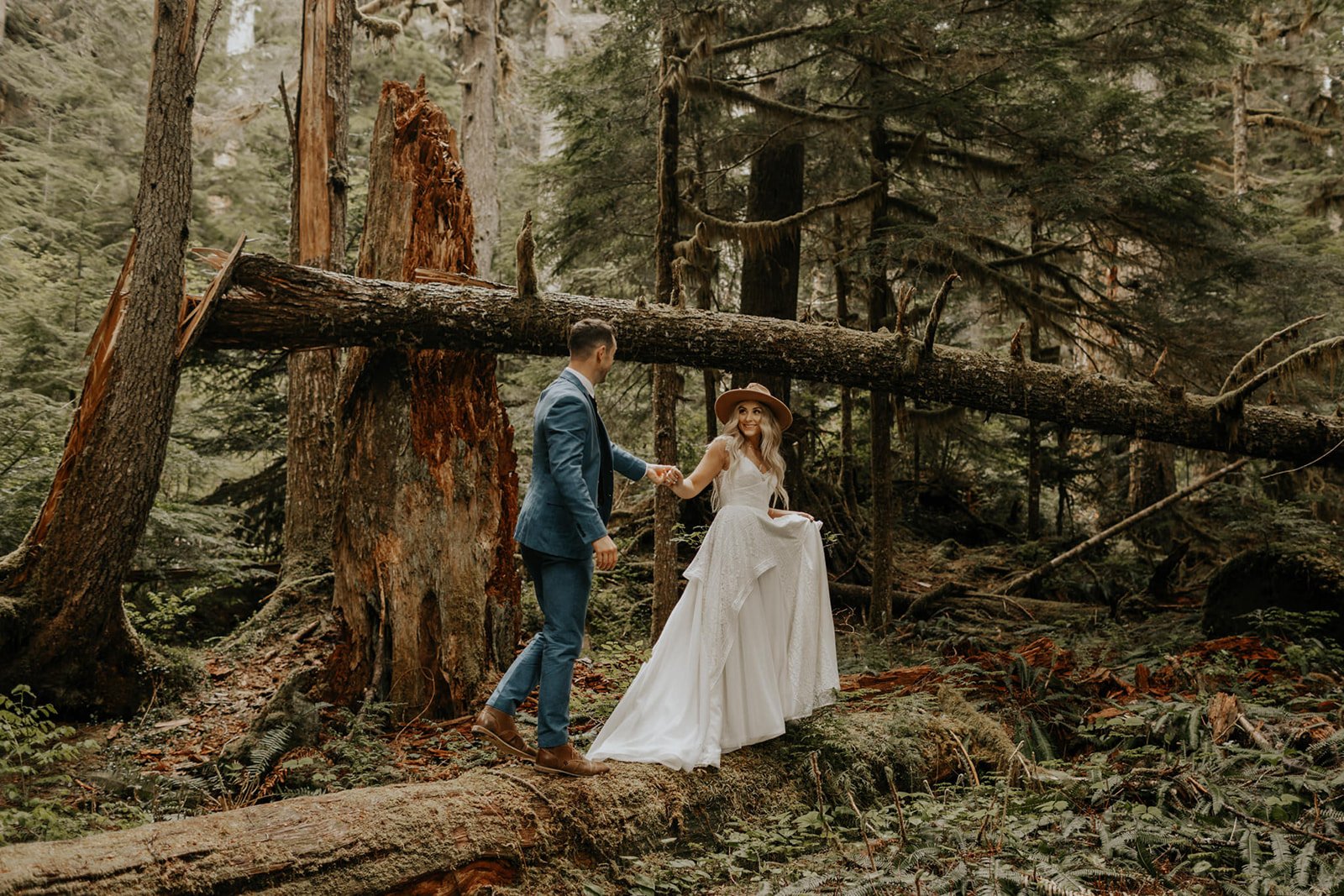 bride leading groom walking on a log in mt. rainier