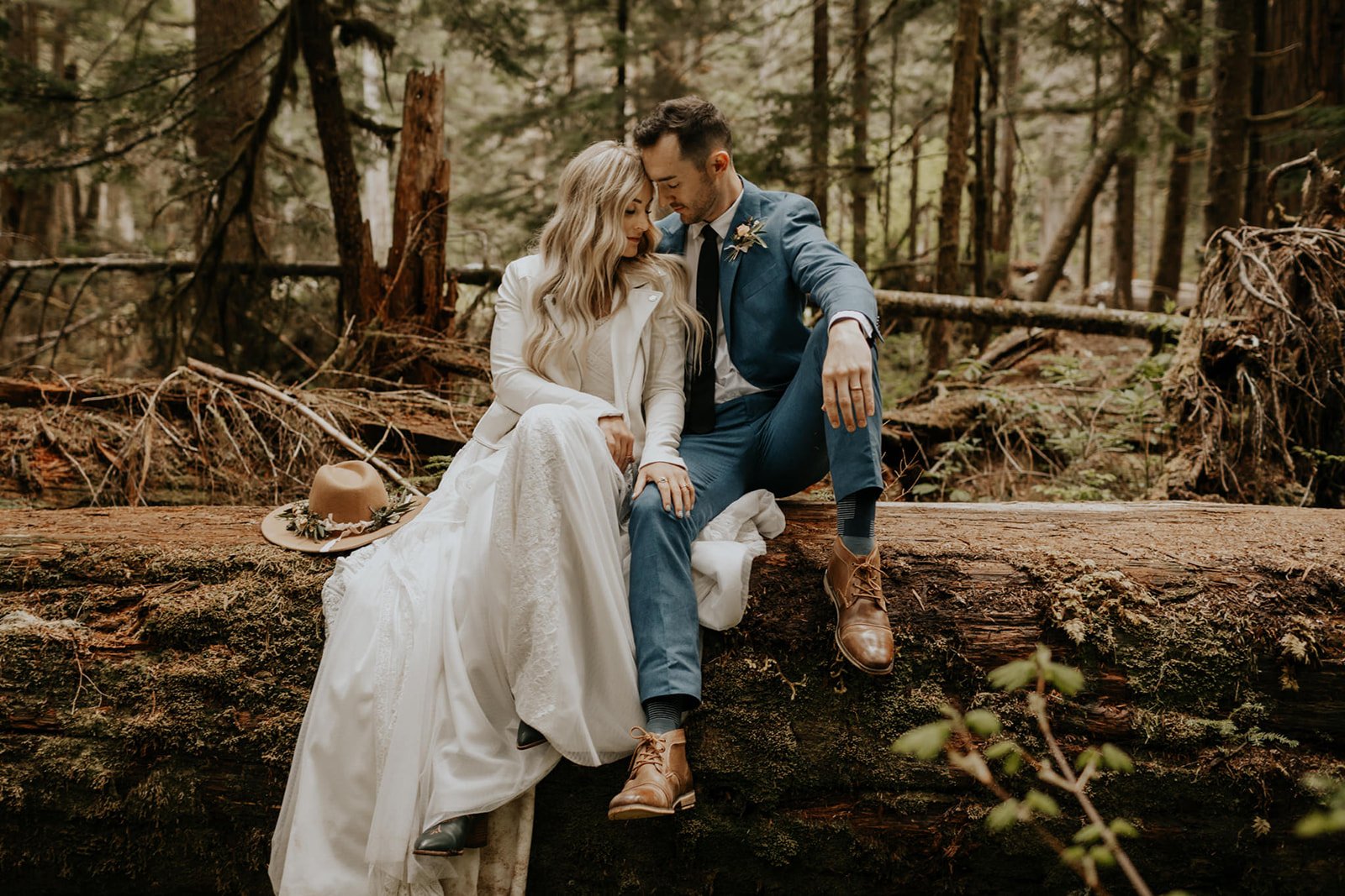 bride and groom sitting on a log in mt. rainier forest