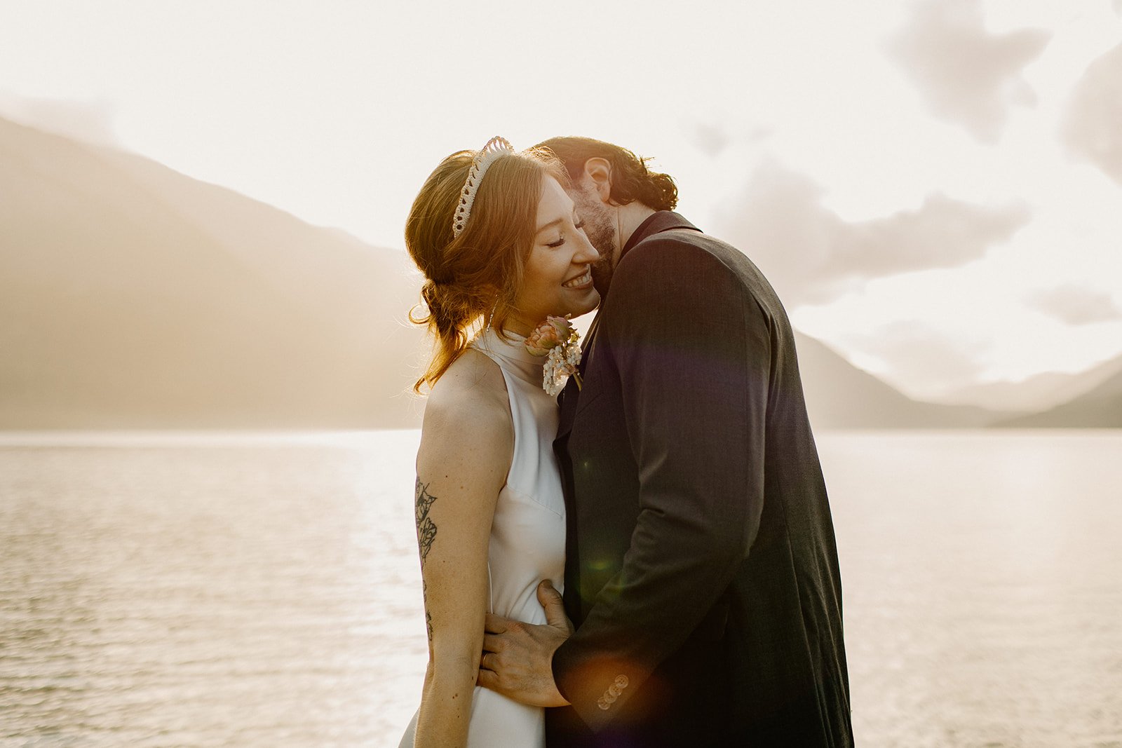 Groom kissing bride on the cheek on the dock at Lake Crescent in Olympic NP