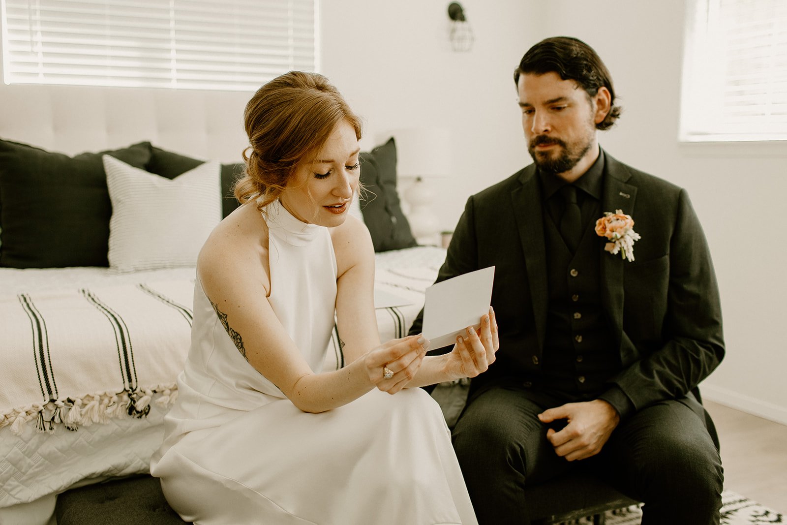 Bride reads letter from her parents while seated next to the groom in their Airbnb