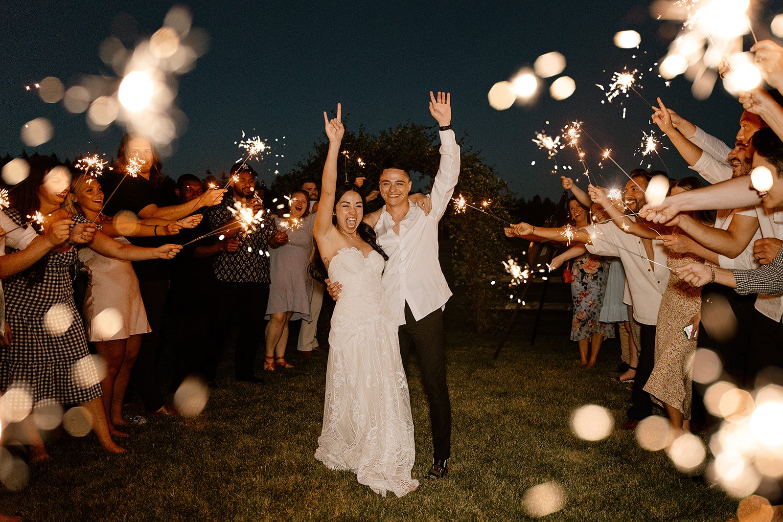 bride and groom fist pumping in celebration during their sparkler exit at their wedding reception