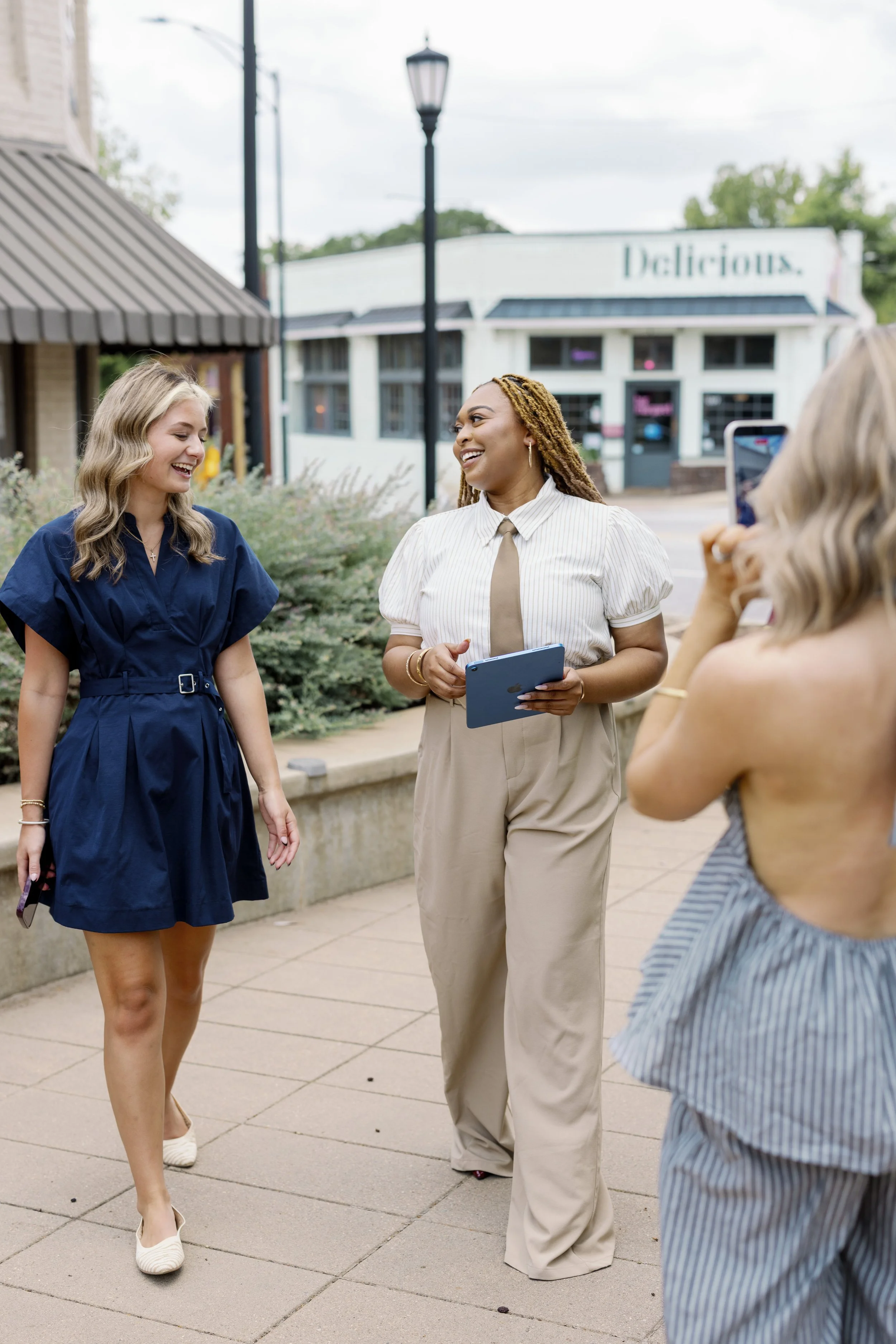 Three women are standing and talking outdoors on a sidewalk for a branding session in Greenville, SC by Melissa Glynn Photography